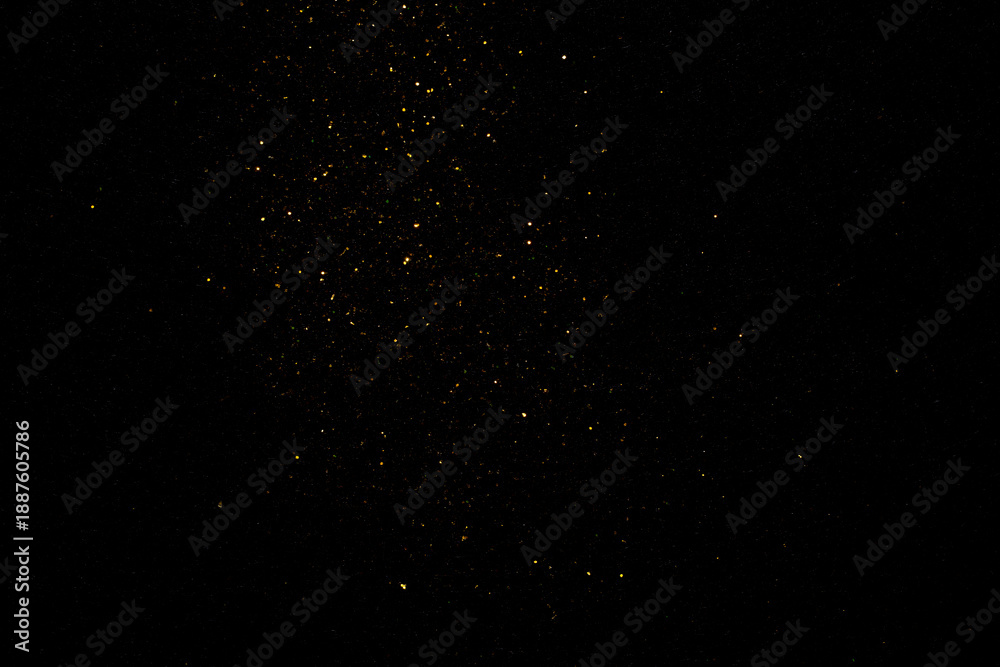 Fototapeta premium group of small golden flakes are scattered on the black surface 