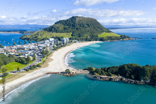 Aerial view of sun-kissed sands meet the turquoise waters beneath the majestic Mount Maunganui, New Zealand, Mount Maunganui, Bay of Plenty Region, New Zealand.