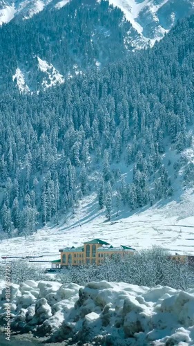 Snowy mountain landscape with buildings and trees in winter wonderland in the city of Kashmir, India.