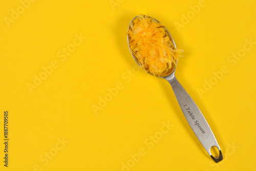 Slika na platnu A top view of a stainless steel measuring tablespoon filled with fresh yellow le