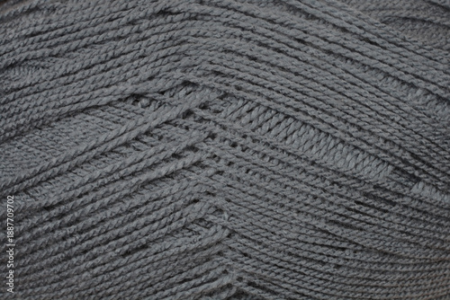 Detailed macro shot of dark gray wool yarn ball showing complex fiber texture and twisted threads in a pattern