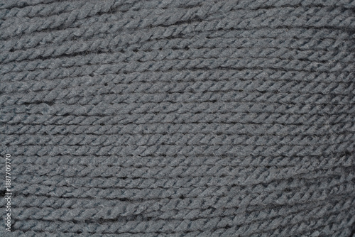 Close up shot of dark gray knitting yarn showing detailed fiber structure and twisted threads arranged in a horizontal pattern