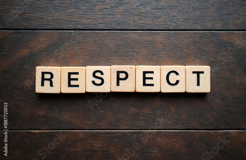 Wooden blocks spell the word RESPECT on a dark wood surface. Concept conveys acknowledgement honor and regard for others. Simple graphic text.