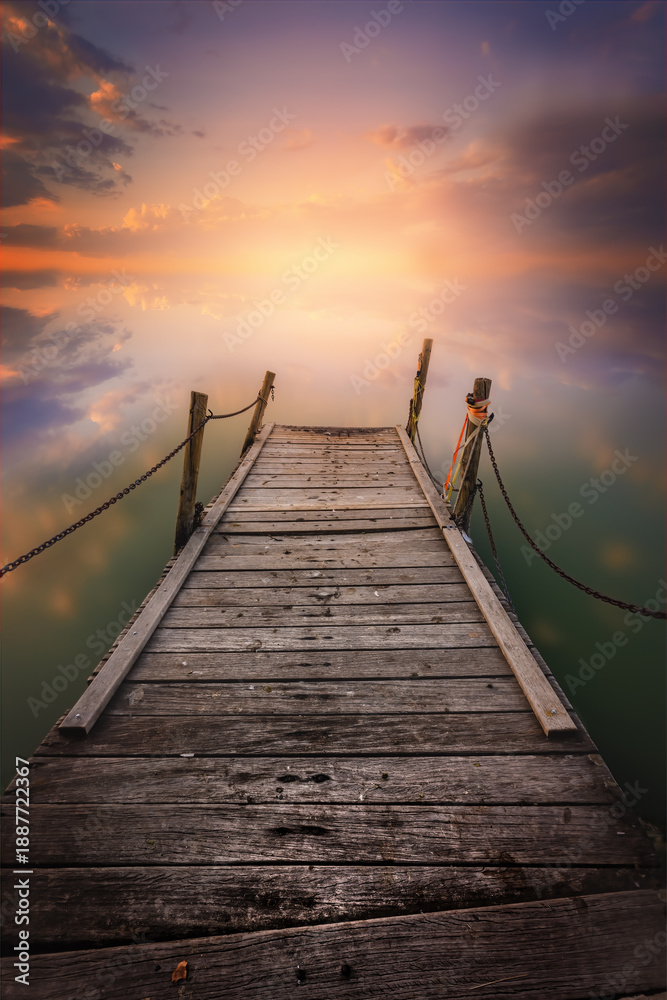 Fototapeta premium Rustic Pier on a Calm Lake with a Dramatic Sunset Sky