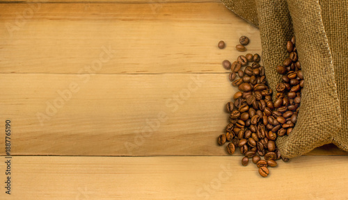 Roasted coffee beans poured from a bag onto a wooden surface