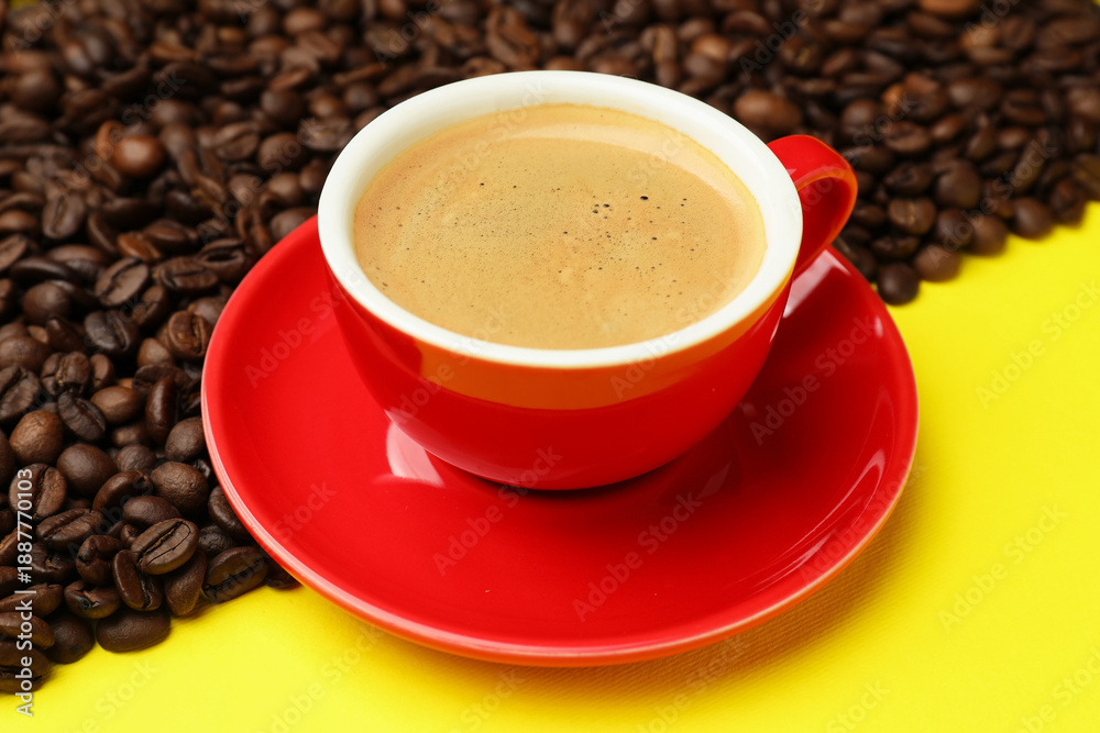 Fototapeta premium Cup with aromatic coffee and beans on yellow background, closeup