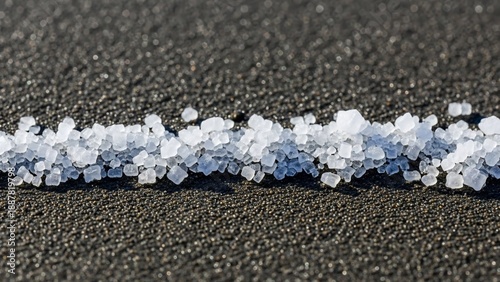Small white salt crystals scattered on dark asphalt surface.
