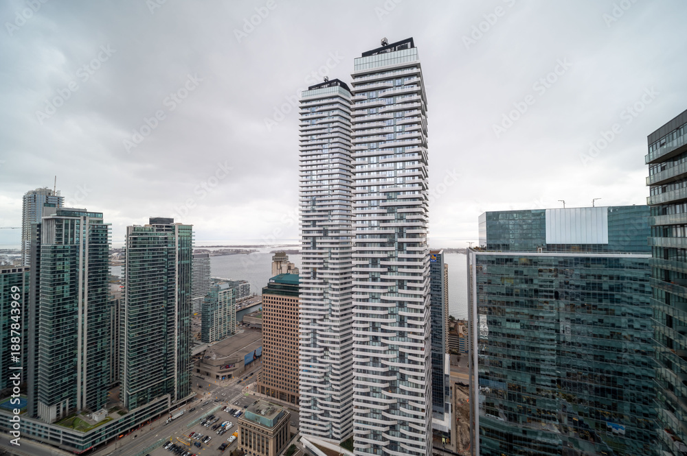 Fototapeta premium Toronto downtown cityscape showcasing a dense cluster of contemporary skyscrapers, residential towers, and corporate offices lining the urban waterfront under a cloudy sky. In mimco