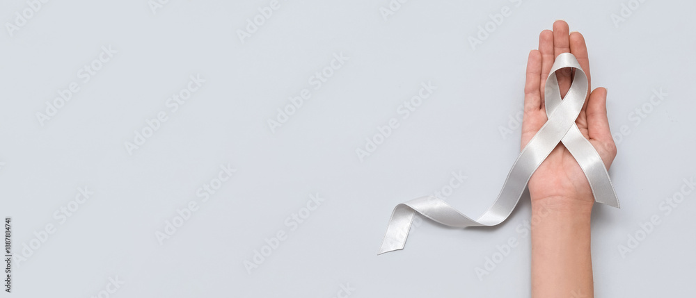 Fototapeta premium Woman holding awareness ribbon on grey background. Brain cancer concept