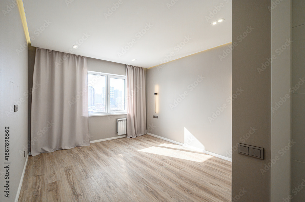 Obraz premium Light, airy room with light wood flooring, neutral walls, large window with beige curtains, recessed ceiling lights, modern wall sconce, white radiator, minimalist design.