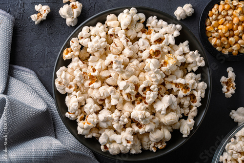 Delicious popcorn in bowl on black  stone table background.

