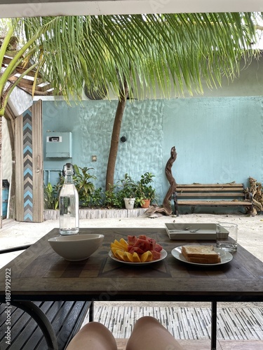 Breakfast on vacation at a hotel. Ukulhas, Maldives. Courtyard, palm trees, fruit, sun, blue wall.
