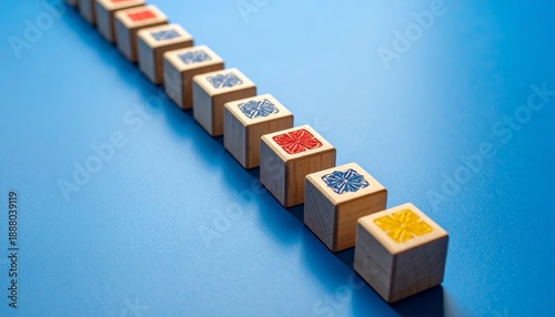 Wooden blocks with geometric patterns in yellow, red, and blue arranged diagonally on blue surface—evoking playful order, crafted rhythm, and visual clarity in a design-focused composition.