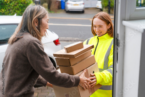 Delivery person hands over packages to smiling recipient on a sunny day outside a house