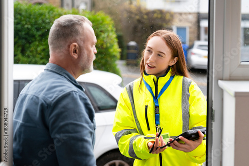Fotografie Worker talks to man at home in front of door during day