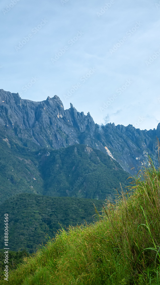 Fototapeta premium Many peaks Mount Kinabalu is highest tropical mountain in Borneo, jagged mountain peaks. Clouds hide in gorges. Geological rise of adolescent mountains continues. Landscape of once Mysterious Island