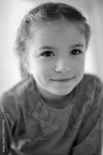 Young girl smiling softly in a cozy indoor setting with natural light