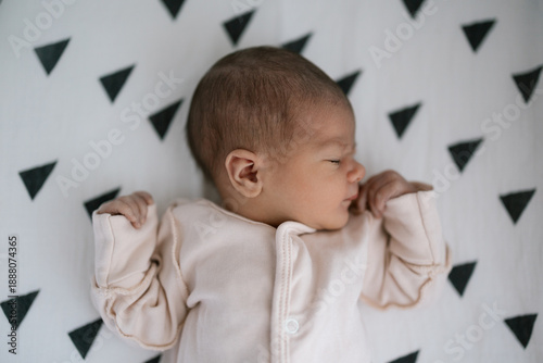 Newborn baby sleeping peacefully on patterned blanket in soft natural light
