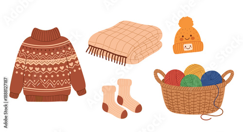 Assorted knitting and winter essentials like a patterned sweater, folded blanket, beanie with a face, socks, and yarn are shown.
