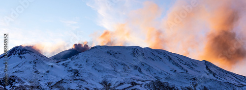 Sunset view of Mount Etna from the north side, as a dramatic plume of volcanic ash ascends into the sky.