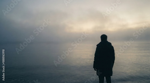 Silhouette of a man walking alone on a sandy beach at sunset by the sea under a colorful sky