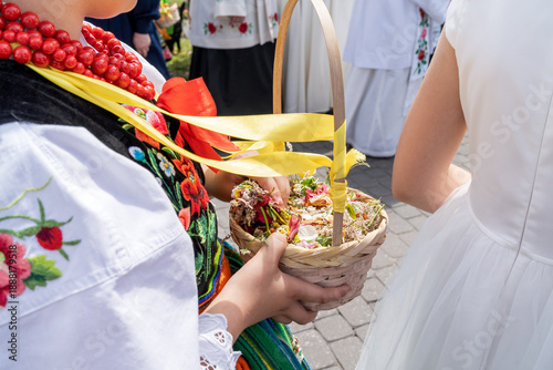 Girls in traditional Polish folk costumes throwing fresh flower petals during Łowicz Corpus Christi procession	