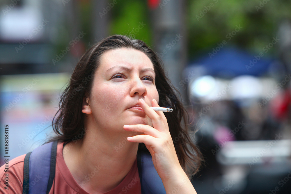 Φωτογραφία Close-up portrait of a thoughtful adult woman smoking a cigarette outdoors on a city street