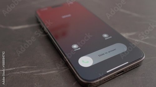 A smartphone sits on a table while an incoming spam call alerts the user. The screen shows options to answer or decline the call clearly.