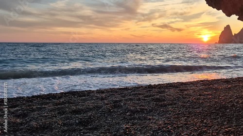 Sunset ocean beach waves lapping pebble shore vibrant sky scenic cliffs tranquil nature travel destination