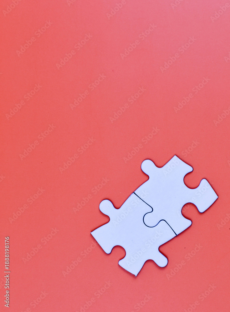 Obraz premium Two interlocked white puzzle pieces on orange background, symbolizing connection, unity, or problem-solving in a minimal visual composition.
