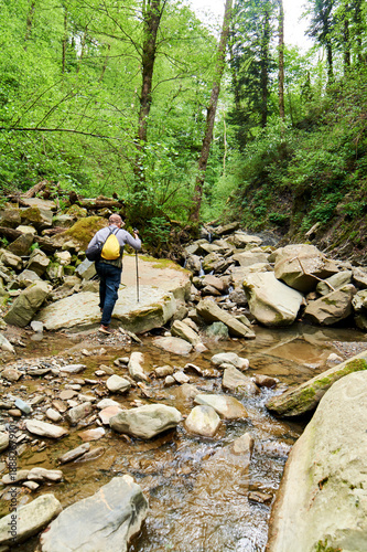 Tableau sur toile Man with small backpack explores river by walking in water, discovering nature's aquatic pathway firsthand
