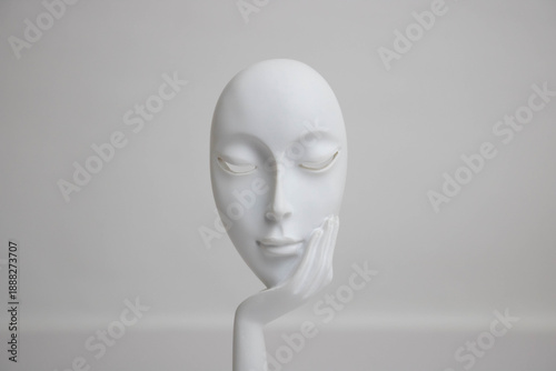 A white statue with a young girl's face resting on her palm
