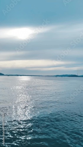 Peaceful seascape featuring calm blue ocean water with sunlight reflecting on the surface under a soft cloudy sky. Ideal for background, nature, travel, meditation, relaxation, and environmental conce