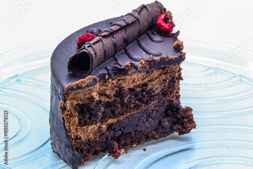 Exquisite dessert with chocolate glaze, decor, and berries. Close-up of a cake slice showing layers of delicate sponge and cream. Perfect for cafe menus and food blogs