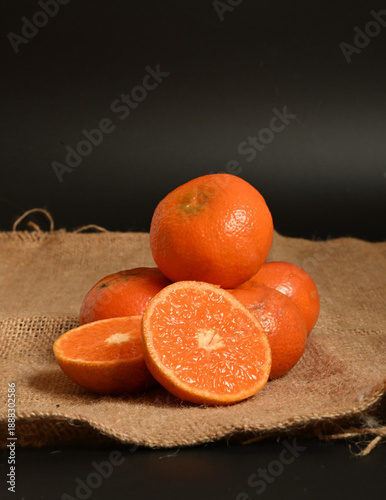 Vertical composition of tangerines on a sackcloth surface against a black backdrop, perfect for artisanal food labels and eco-branding