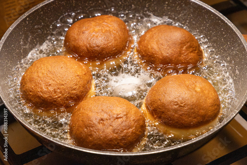 Photography Golden brown doughnuts frying in hot oil pan for traditional Fat Thursday celebration homemade sweet pastry dessert cooking process and delicious culinary snack background