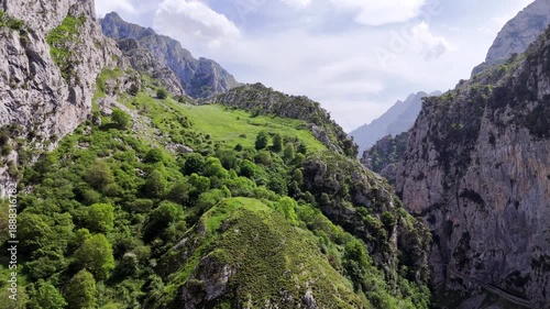 Picturesque meadow in the Picos de Europa mountains of Spain surrounded by jagged mountain peaks rising high into the sky. Aerial drone video in Cares Gorge canyon Picos de Europa.