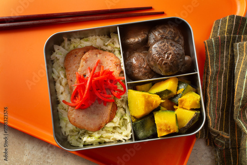 A top down view of a bento box, featuring spam and slaw.