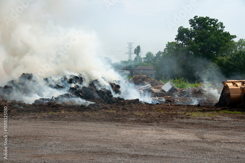 A large heap of hay, wood and debris emits dense smoke, creating an industrial, smoky scene ideal for topics like pollution, waste management, and environmental impact.
