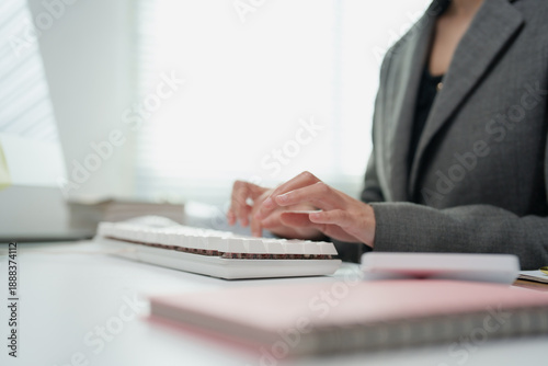 Businesswoman hands engage in active typing on a white computer keyboard, symbolizing productivity, professionalism, and dedicated work within a modern office environment