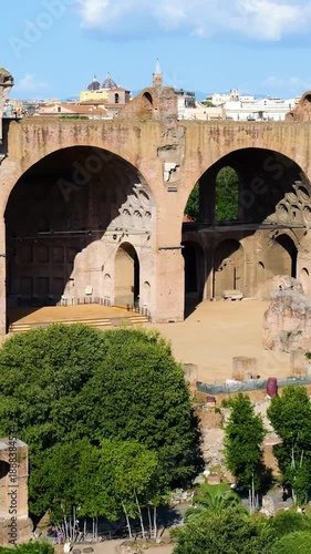sunlit basilica maxentius constantine monumental brick arches above green gardens visitors stroll through rome close view italy roman empire emperor of 