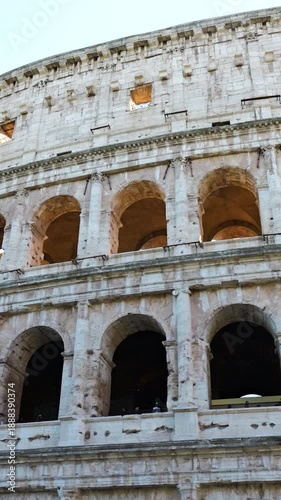 low colosseum stacked arcades weathered stone facade rhythmic arches curve beneath pale sky reveals wide angle view rome italy roman empire emperor low-angle 