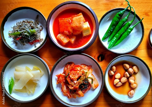 Schilderij op canvas Top view of traditional Korean side dishes set including Kimchi, stir-fried anchovies, and green peppers on a wooden table