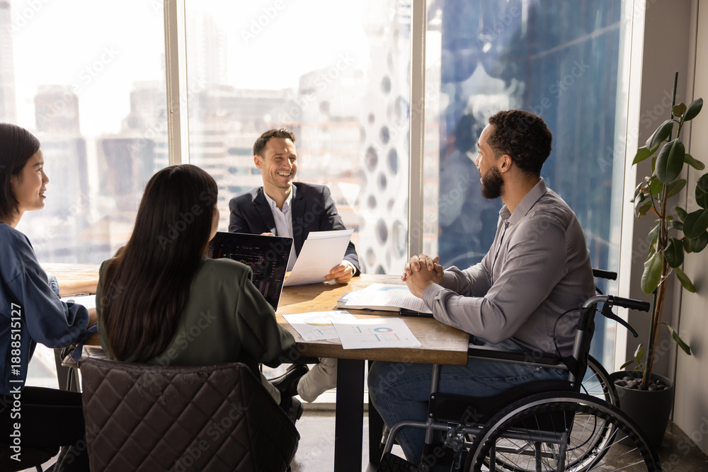 © fizkes - Happy African American project manager with disability offering business idea for brainstorming on group meeting. Diverse team of analysts discussing marketing strategy for project