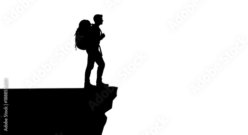 Silhouette of a hiker with backpack standing on the edge of a cliff  overlooking the horizon