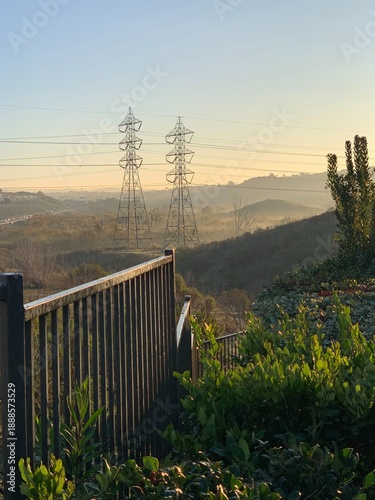 Large electricity pylons and transmission lines standing in the thick morning haze of Carlsbad, CA.