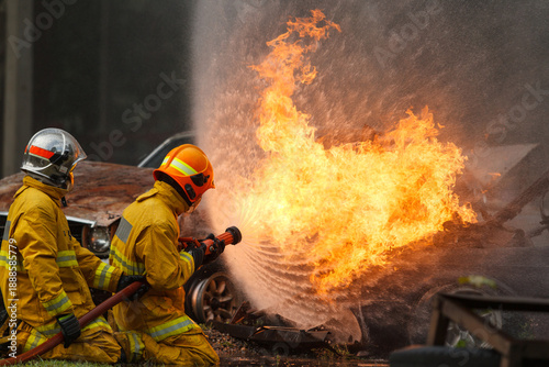Firefighters extinguishing burning car during emergency response