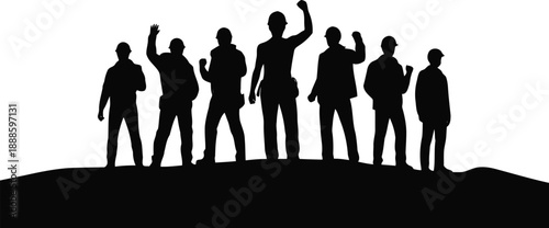 Group of diverse construction workers wearing hard hats stand on a hill raising fists and waving