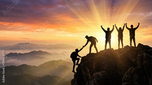 Silhouettes of triumphant people on a mountain peak with arms raised at sunrise summit
