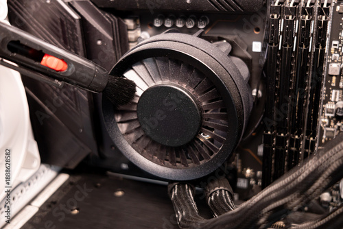 Technician hand cleaning black CPU fan blades with a brush for better computer performance
